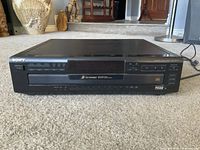 Front view of the Sony 5-disc CD changer showing brand label, buttons, and display panel.