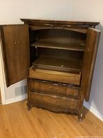 Photo showing armoire with doors open, inside shelves and drawer visible.