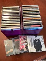 Two stacks of assorted music CDs in jewel cases arranged vertically, showing spines with artist and album titles.