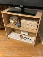 Photo of a small wooden bookshelf with two shelves holding various items, but contents not included in sale.