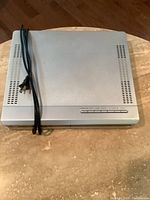 Top view of the silver DVD player placed on a marble surface, showing ventilation slots and power cord.