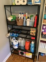 Photo shows black metal shelving unit with four mesh shelves filled with various household cleaning supplies and paper products for context. Shelving unit dimensions approximately 31x10x61 inches. Contents not included for sale.