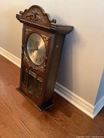 Side angled view showing wood casing and carved details of the clock