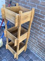 Front view of the three-tier wooden storage unit showing all three open compartments and corner post detailing.