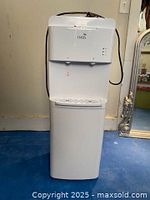 Full view of Oasis water cooler dispenser showing the entire unit including base, drip tray, and water dispenser area.