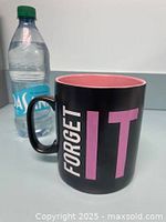Oversized ceramic mug with black exterior and pink interior. Dasani 20oz water bottle shown beside for size reference.