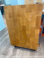 Top view of the wooden butcher-block style foldable table top showing wood block pattern and surface stains.