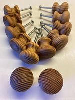 Set of 12 wooden drawer pulls arranged in a semi-circle showing natural woodgrain and screws attached for installation.