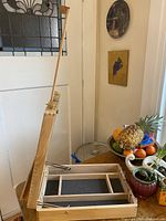 Open adjustable wood easel showing interior storage with compartments and foam lining.