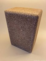 Photo of a solid cork yoga block standing on its smallest side, showing texture and edges.