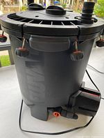 Full side view of the black cylindrical Fluval FX6 aquarium canister filter showing lid locking clips and power cord attachment.