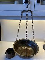 Full view of the large copper hanging planter with chain and smaller copper pot beside it.