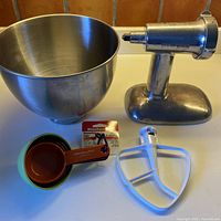 Photo showing all items: metal mixing bowl, flat beater, new measuring cups, metal grinder attachment