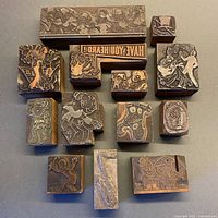 Overview photo displaying all 13 metal or copper entertainment-themed stamps on wooden blocks arranged on a surface.