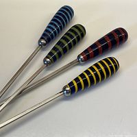 Close-up of the handles of the four BBQ skewers showing blue, green, red, and yellow glass blown striped handles.