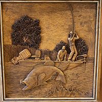 Close up detail of the wooden relief carving showing fishing scene with two men in a boat and a large fish jumping.