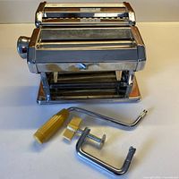 Full view of stainless steel pasta maker with rollers and cutting attachments
