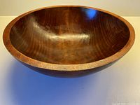 Side angle view showing the overall shape, wood grain, and finish of the maple bowl.