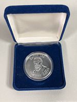 Silver commemorative coin in blue velvet and satin-lined display case.