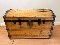 Front view of the domed pine trunk showing iron iron straps, lock plate, and two latches.