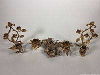 Photo of the three gold gilt metal Italian Tole Florentine wall sconces shown together on a white background. Pair one-arm sconces and single double-arm sconce all visible revealing shape and detailing.