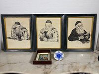 Three framed lithograph black and white sketches by Ivan Sors of elderly Jewish men, one small framed portrait painting, and blue Mogen David decorative plate on marble surface.