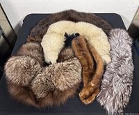 Five vintage mink fur shawl collars arranged on a flat surface showing color variety and texture.