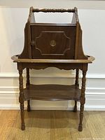 Front view of walnut humidor stand with cabinet door closed and circular ashtray recesses on top sides.