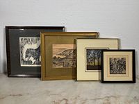 Four framed artworks displayed side by side with different frame styles and visible wear