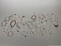 Photo showing an array of 21 freshwater pearl necklaces and bracelets with mixed pearl colors and styles, some featuring 925 silver clasps.