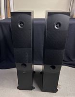 Front view of both speakers with cloth grilles installed showing dome tweeters and lower sections