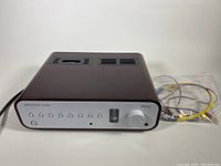 Front-left view showing amplifier in rosewood case, tube visible on right and included cables in bag