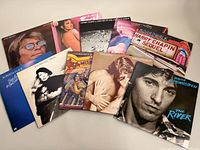 Photo showing all 10 vinyl record albums spread out on a flat surface, featuring Bruce Springsteen, Harry Chapin, Barbra Streisand, John Denver, Roberta Flack, Joni Mitchell, and Kristofferson albums.