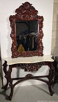 Full view of the mirror and table together showing carved wooden details and marble top.
