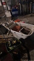 Photo of large white Rubbermaid garden cart with various yard supplies inside including empty plant pots.