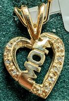 Close-up photo of the heart-shaped pendant showing front diamond accents and 'Mom' lettering