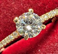 Close-up of round brilliant center diamond in six-prong yellow gold setting
