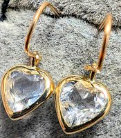 Close-up front view of the pair of 10K yellow gold earrings with clear faceted heart-shaped moonstone stones on a soft gray background.