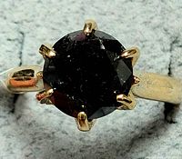 Top view of ring showing round black diamond and gold prong setting