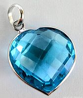 Close-up front perspective showing heart-shaped blue topaz with checkerboard facets and white gold bezel setting.