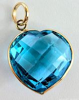 Close-up of heart-shaped blue topaz pendant set in yellow gold showing the checkerboard cut and bail attachment.