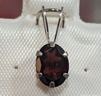 Close-up front view of oval garnet pendant in 10K white gold.
