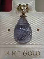 Front view of 14K gold pendant showing carved Iolite gemstone and small diamond, displayed on white textured card with '14 KT. GOLD' printed in gold lettering.