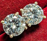 Close-up of two round brilliant diamonds in four-prong white gold settings on red fabric