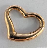 Photo showing polished 18K yellow gold heart-shaped pendant with smooth rounded edges and hollow center