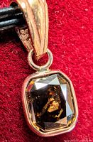 Close-up front view of pendant showing cushion cut diamond with brown color and inclusions