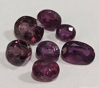 Group of six loose oval faceted rubies on white background