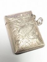 Closed view of the rectangular silver lighter box showing engraved floral and leaf design and attached ring.