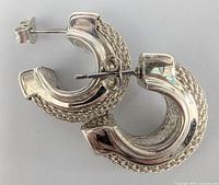 Silver hoop earrings, side view showing textured woven outer surface and polished inner section with post and butterfly clasp