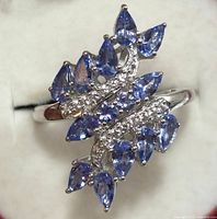 Front view of the silver ring showing pear-shaped tanzanite stones arranged amidst two rows of white topaz stones.